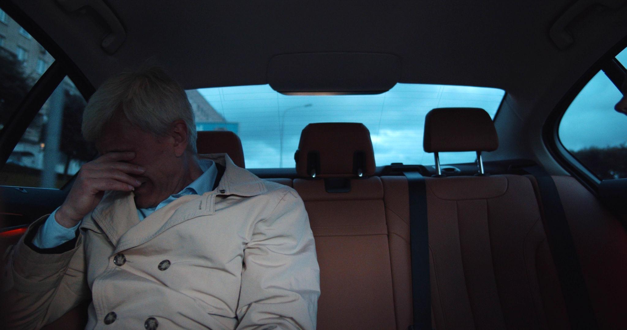Passenger sitting alone in the back seat of a moving vehicle at dusk