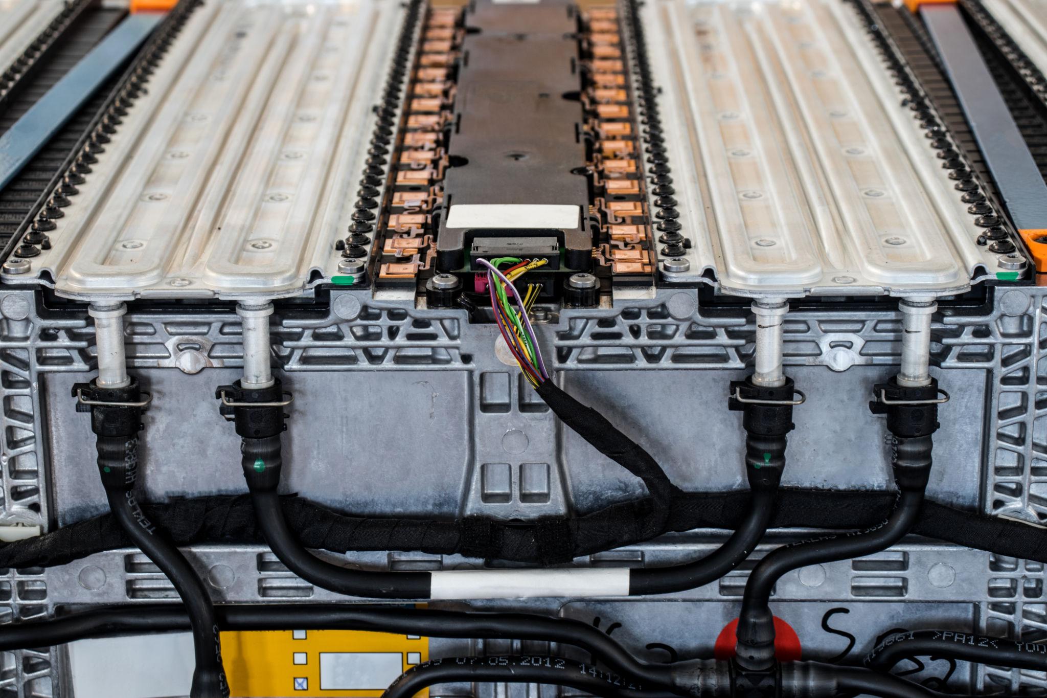 Close-up of an EV battery pack showing liquid cooling channels, busbars and wiring harness